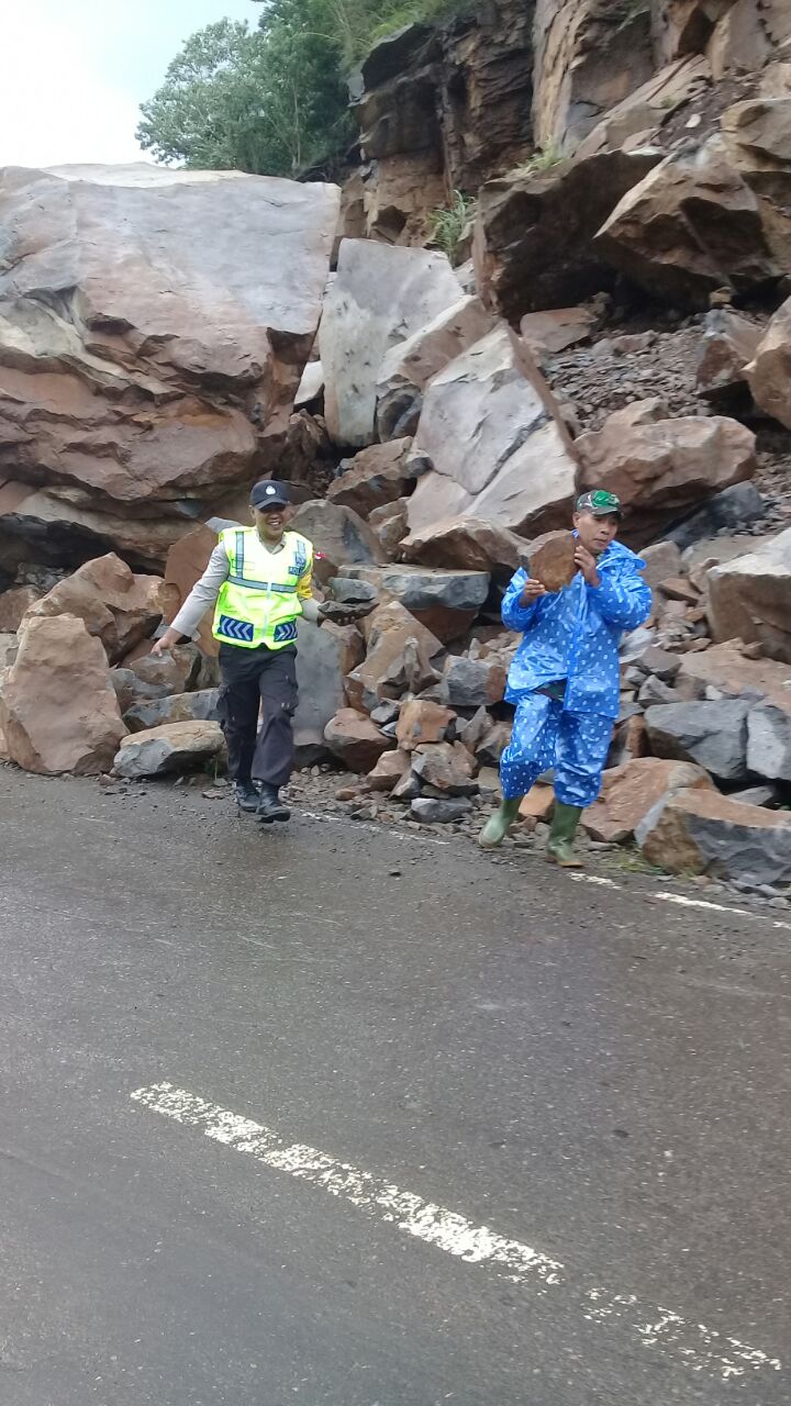 Bhabinkamtibmas Polsek Wolowaru bersama babinsa dan warga setempat bergotong royong membersihkan material di jalan negara yang tertimpa longsor